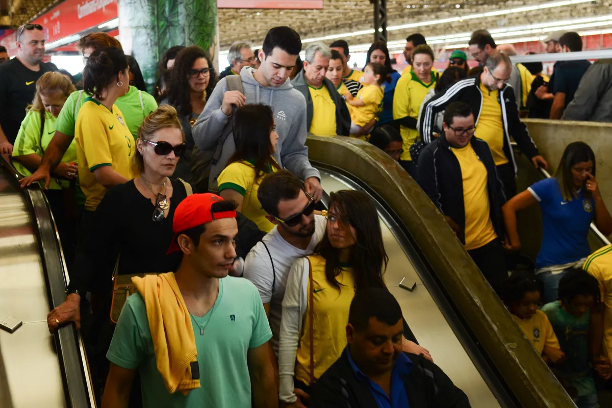 Crowd of fans in yellow Brazil shirts packed on an escalator at Corinthians-Itaquera station in São Paulo