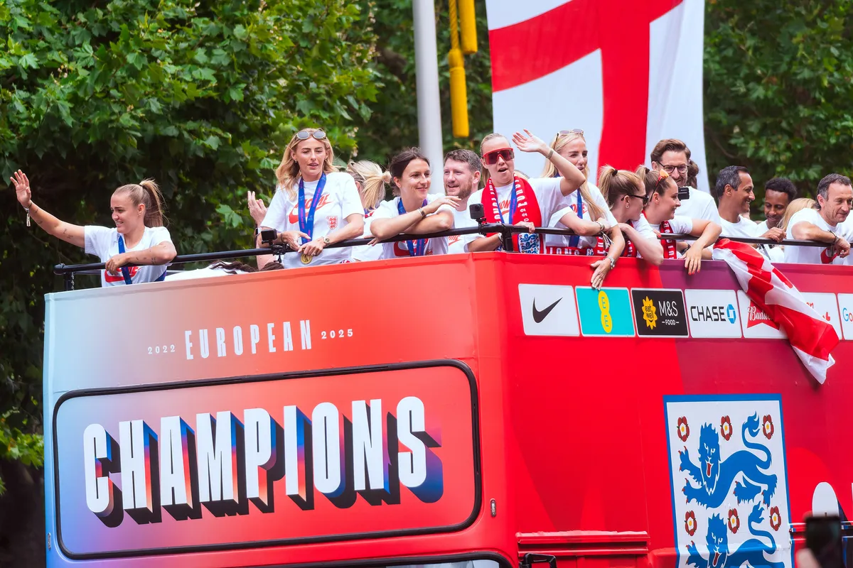 England players wave from the top deck of an open red bus with a Champions banner during the Euro 2025 victory parade in London