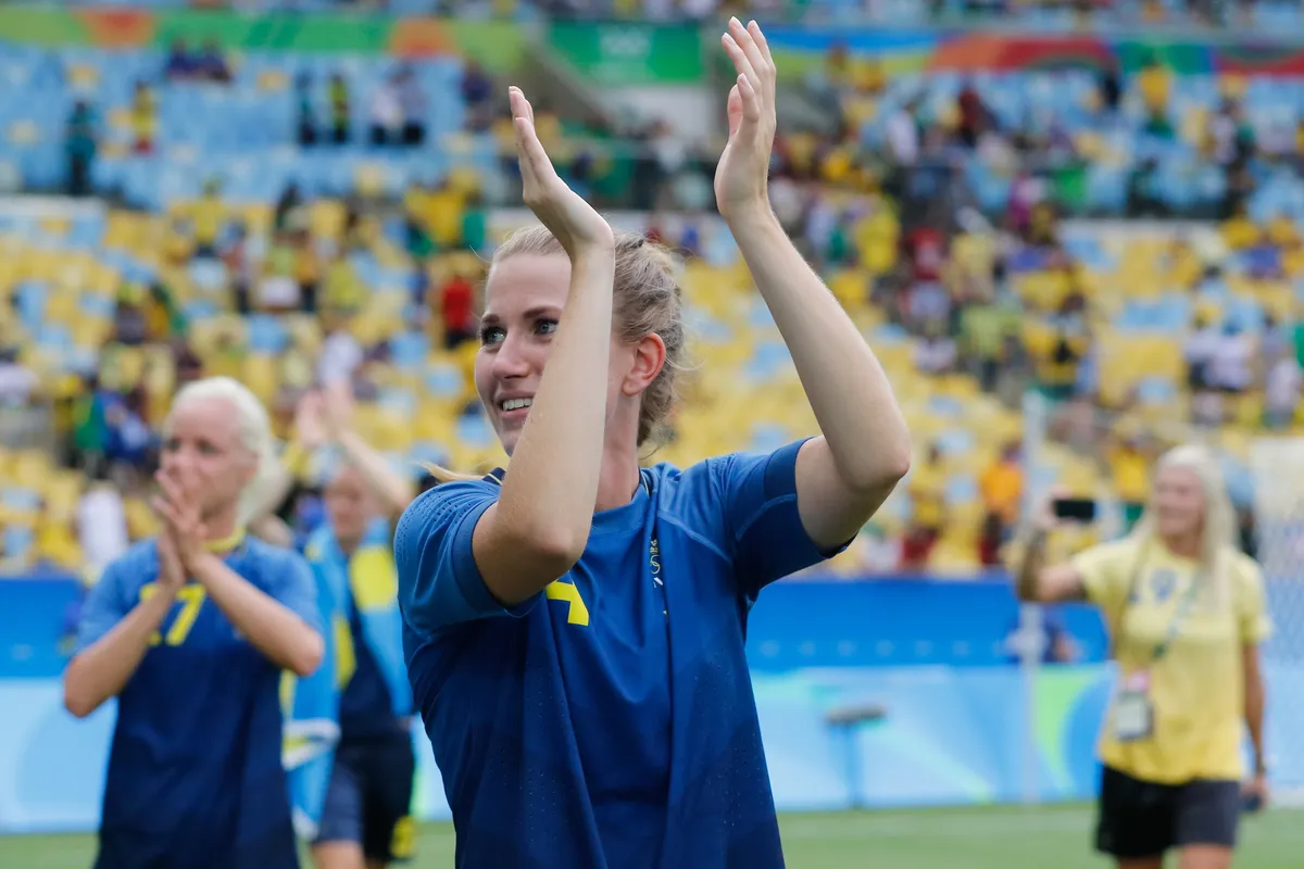 Players in blue applaud the fans after a match at the Maracanã, with rows of yellow and blue seats behind them